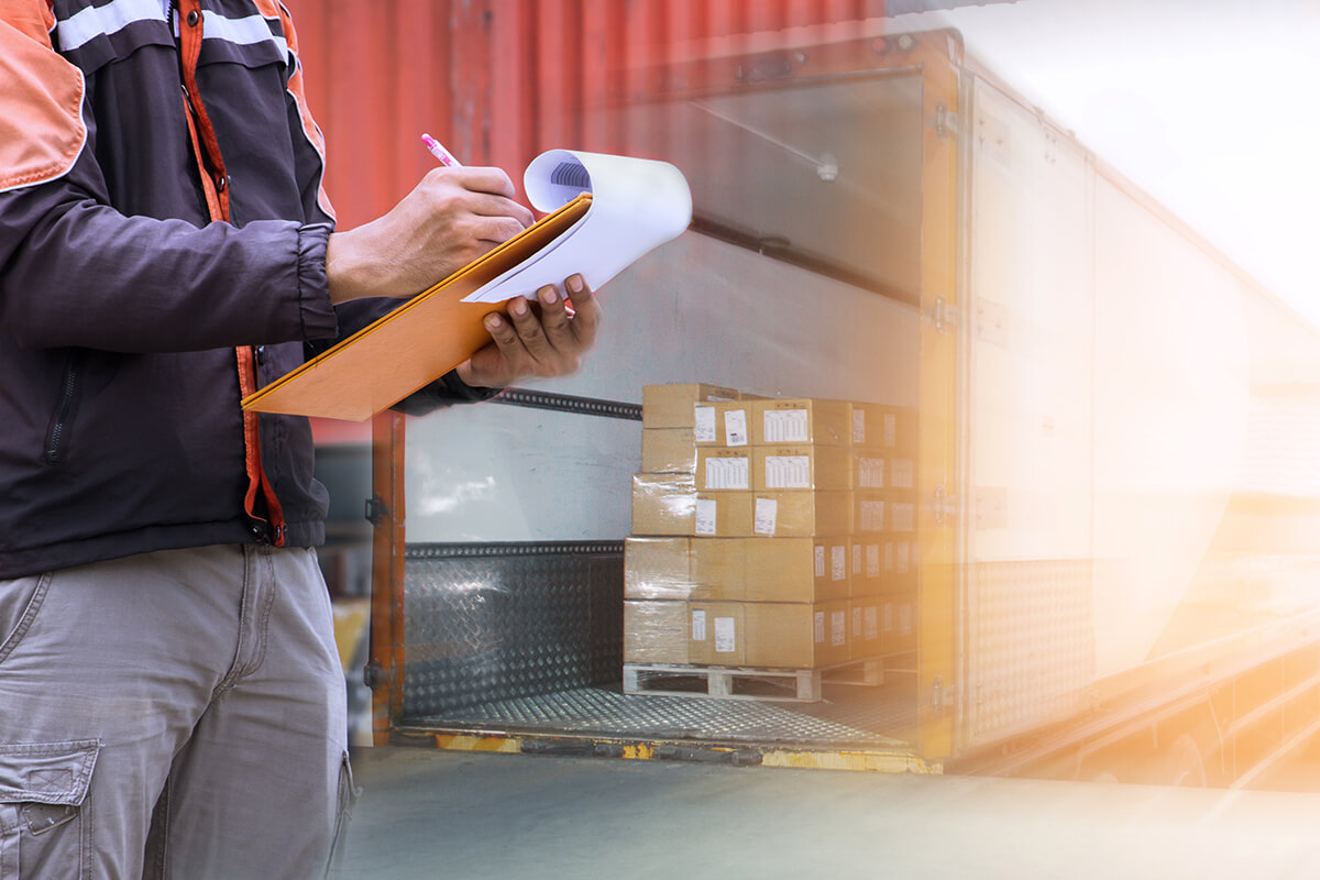 worker doing paperwork in front of container