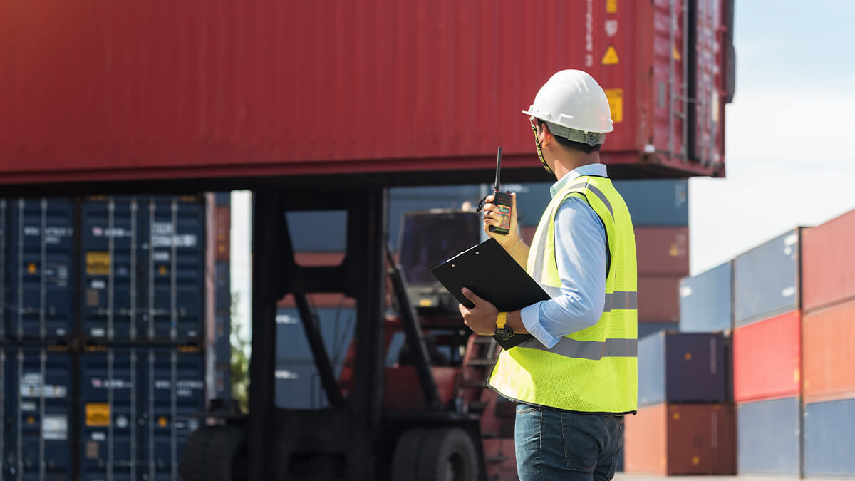 Worker in front of containers. Person is communicating on radio