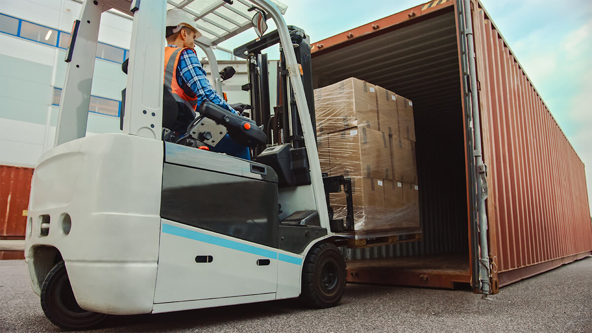 Forklift worker removing items from container.