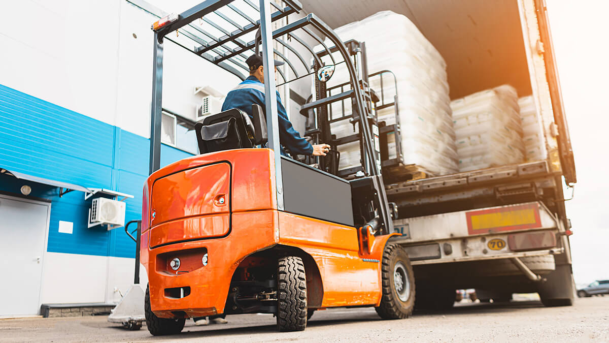 Individual using a forklift to unload goods from truck