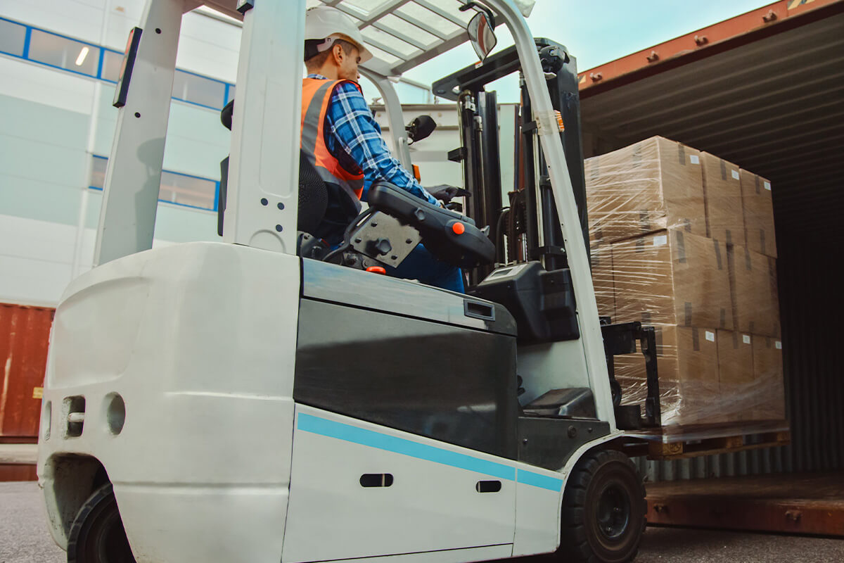 Working handling ax forklift taking inventory out of a shipping container